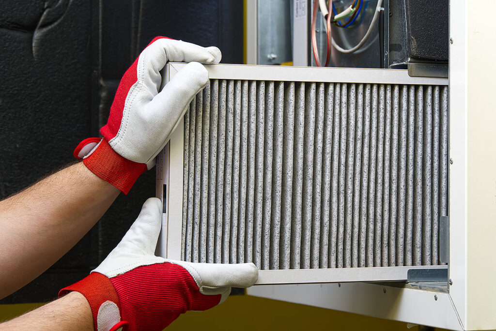 A technician is replacing an air filter in an HVAC unit. This image illustrates the maintenance of an air filtration system to ensure proper indoor air quality.