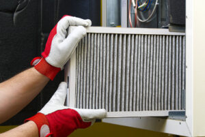 A technician is replacing an air filter in an HVAC unit. This image illustrates the maintenance of an air filtration system to ensure proper indoor air quality.