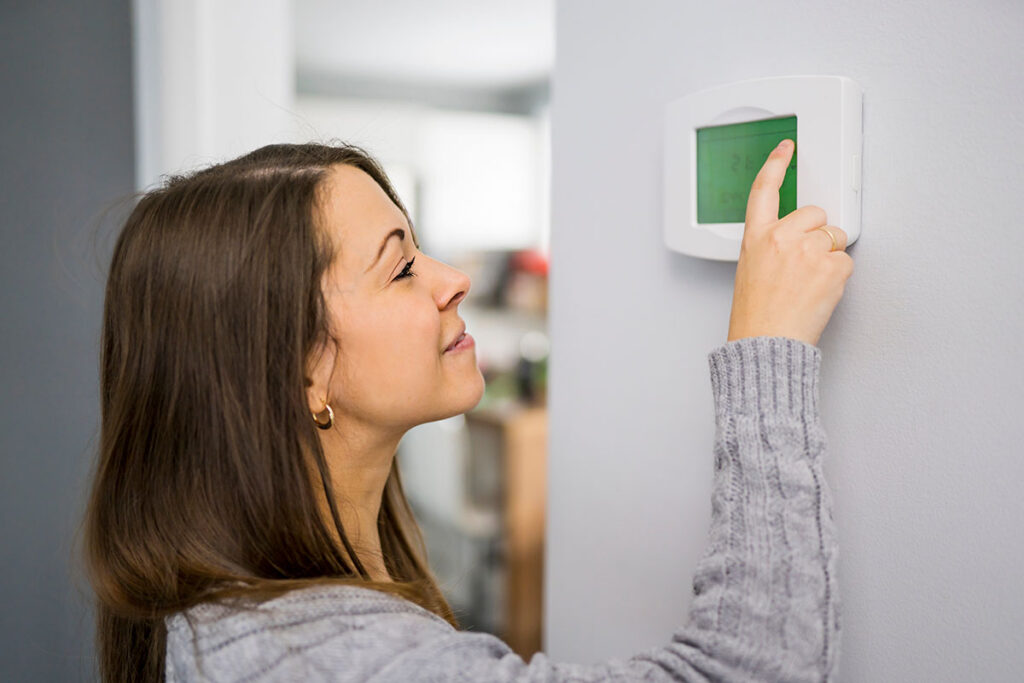 Woman sets the thermostat in her home
