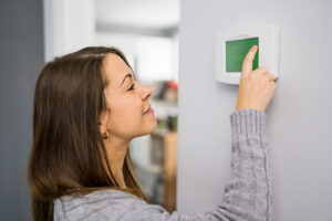 Woman sets the thermostat in her home