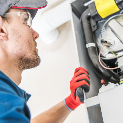 | Air Conditioning Specialists A technician wearing protective glasses and gloves performs a heating system inspection as part of a heating maintenance checklist. The image highlights the importance of regular maintenance to ensure efficient and safe heating system operation.