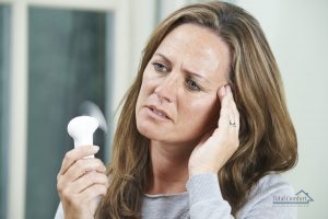 woman using tiny hand-held fan to help cool down in hot weather