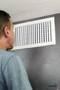 | Air Conditioning Specialists man standing in front of an AC vent