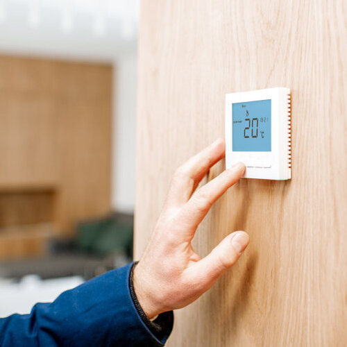 Adjusting room temperature with electronic thermostat at home to save on energy costs