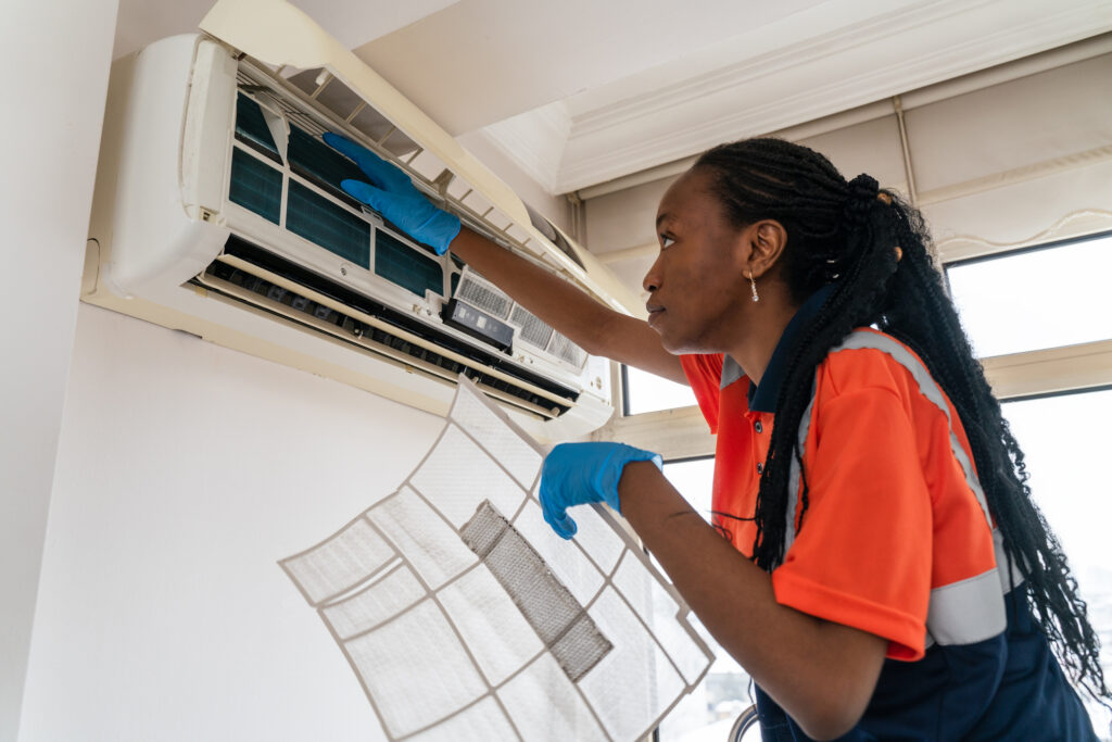 African American female HVAC tech fixing HVAC indoor unit